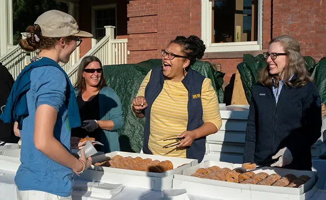 莎拉Willie-LeBreton passes out cider donuts to students on Mountain Day